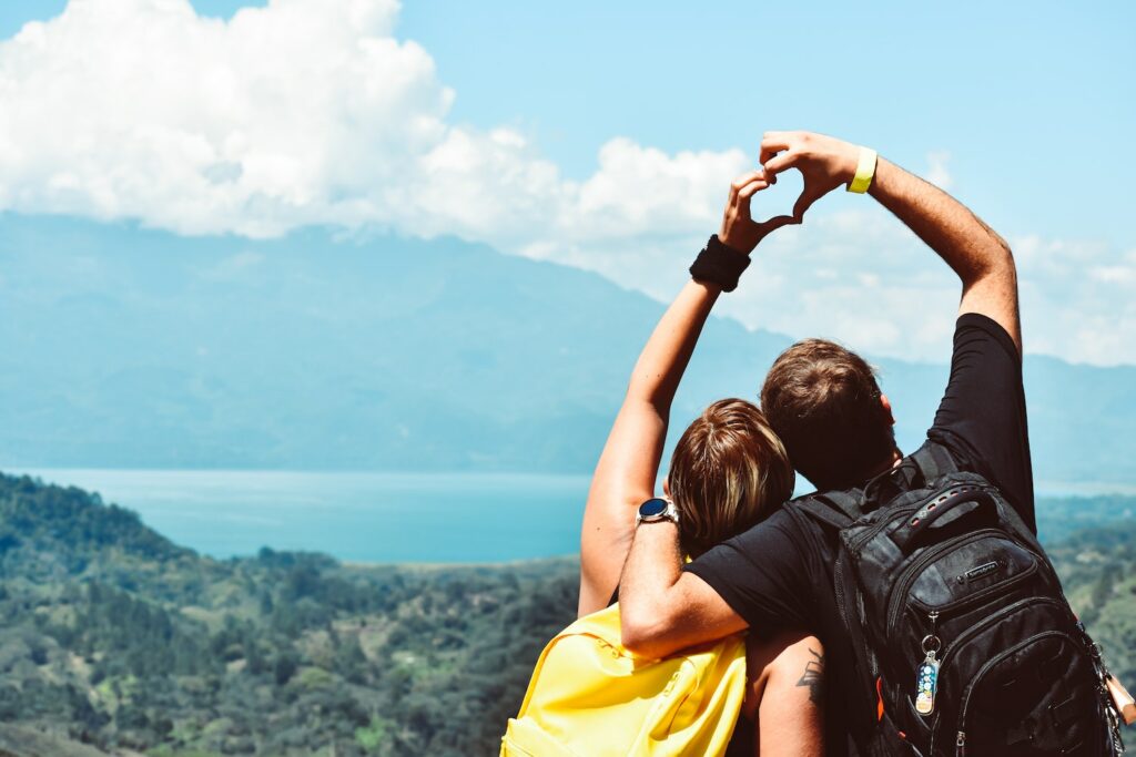 Two travellers make a heart shape with their hands